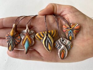 A person displaying new ceramic Yoni Talisman pendants.
