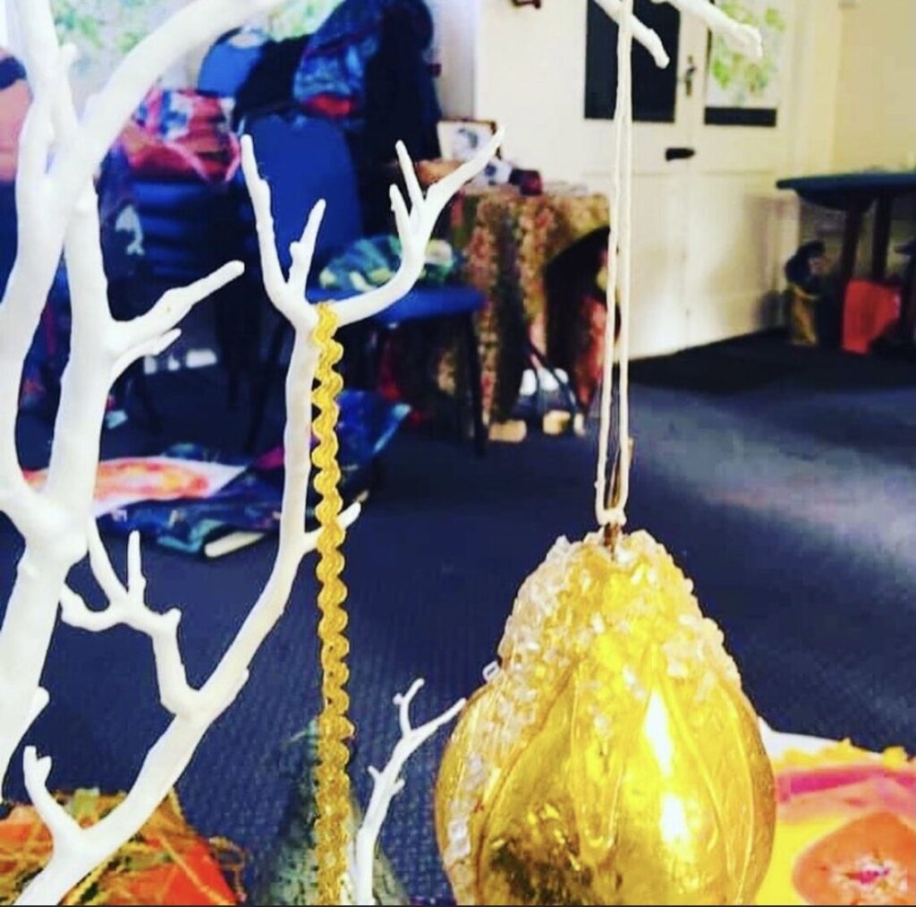 A tree decorated with gold ornaments and twigs.