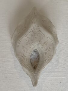 A Yoni Lamp, a white ceramic candle holder on a white wall.