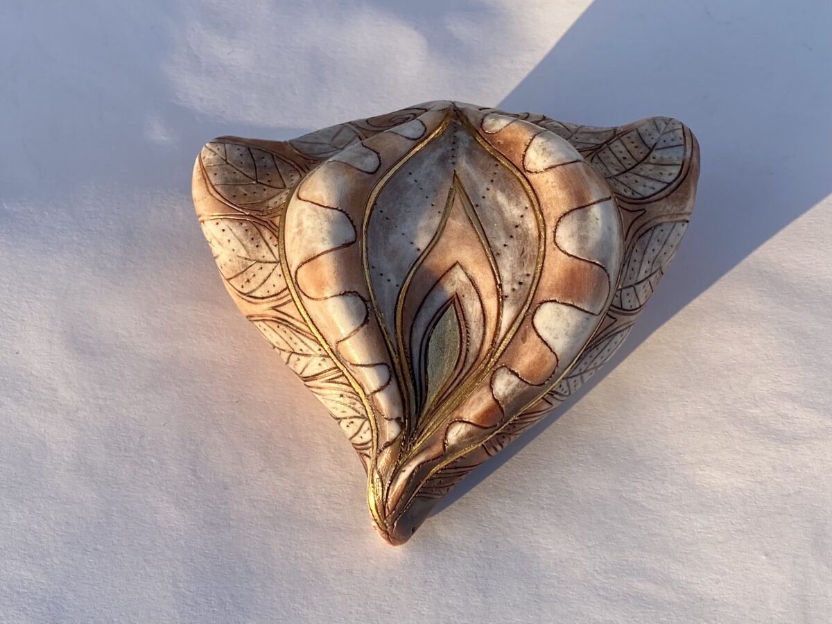 A brown and gold leaf shaped ashtray on a white surface.