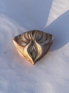 A handcrafted wooden plank with an intricate golden design.