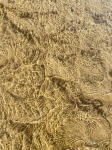 A sandy bottom illuminated by the light in the water.