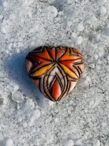 A new work of art featuring a Yoni Talisman carved into a heart-shaped stone.