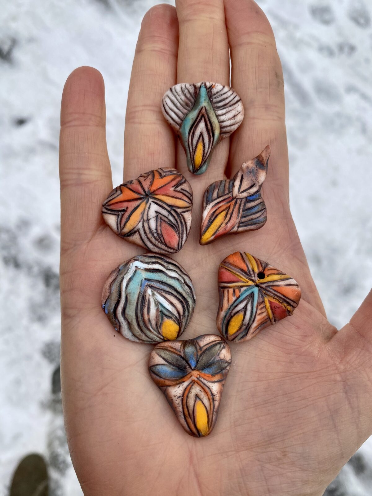 A person's hand showcasing a collection of dazzling Yoni Talisman pieces.