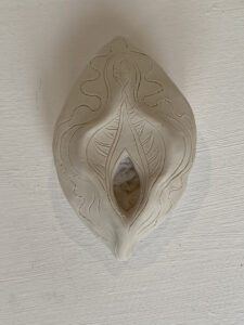 A Yoni Lamp featuring a unique design on a white ceramic piece.