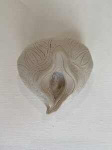 A white ceramic heart shaped Yoni Lamp on a white wall.