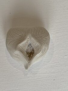 A white ceramic Yoni Lamp in the shape of a heart on a white surface.