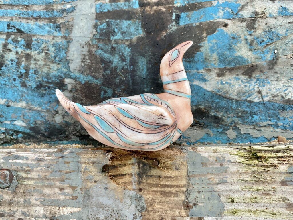A swan sitting on top of a blue wall.