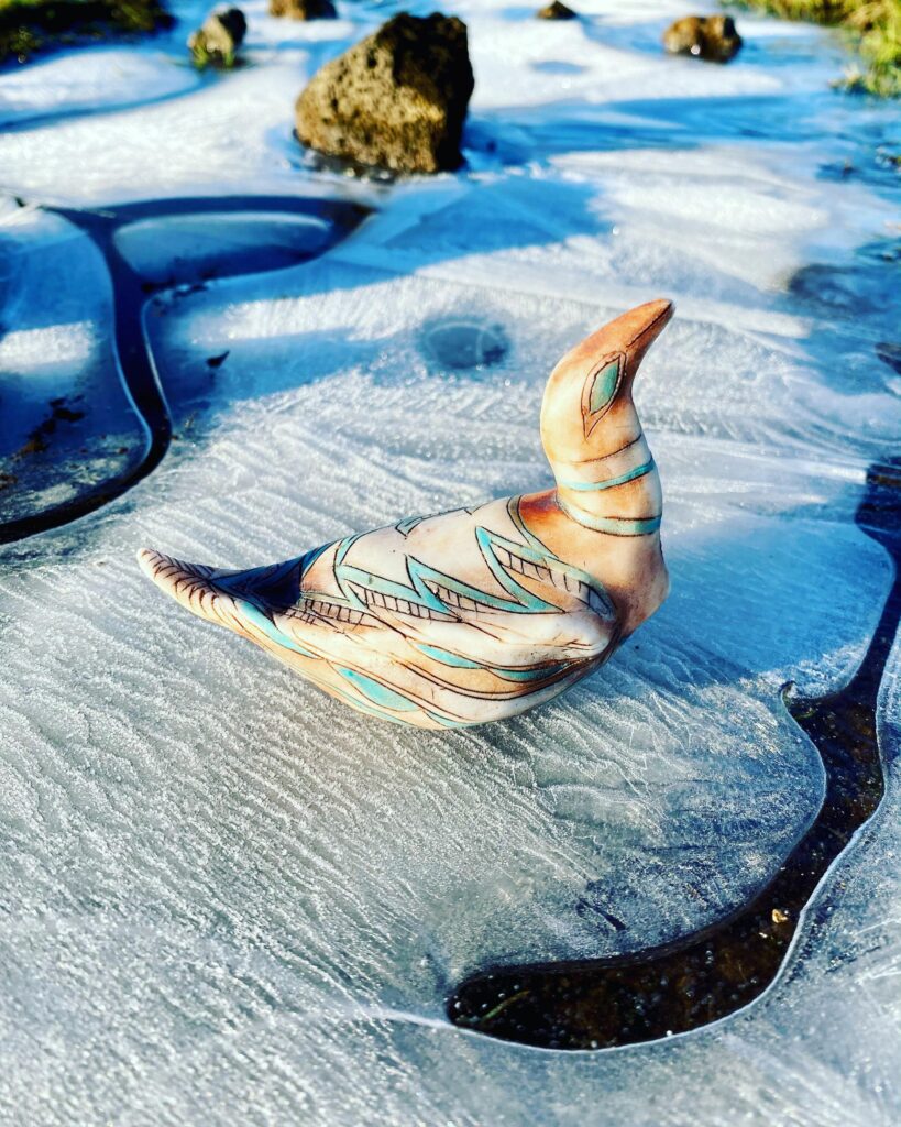 A ceramic bird sitting on the ice.