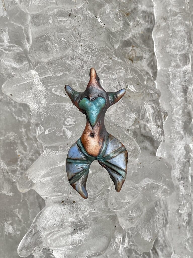 A blue and green mermaid sitting on top of ice.