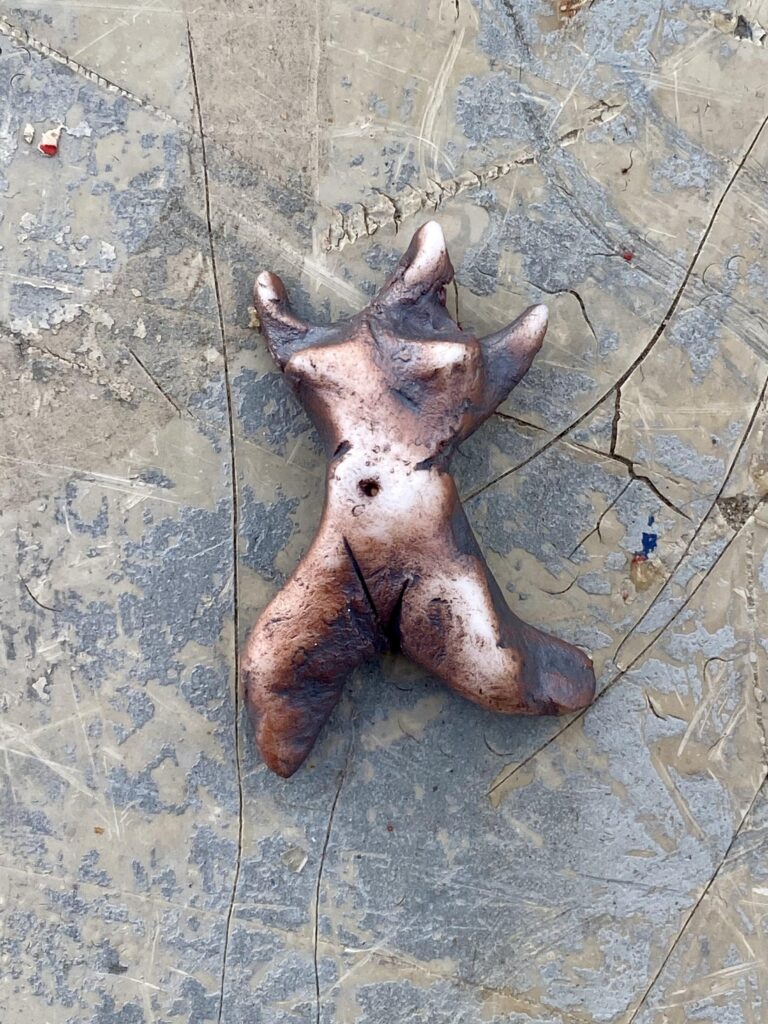 A clay sculpture of a man laying on the ground.