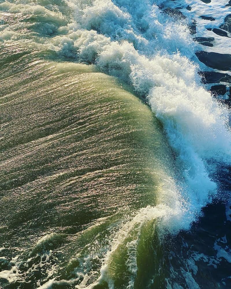 An aerial view of a wave crashing in the ocean.