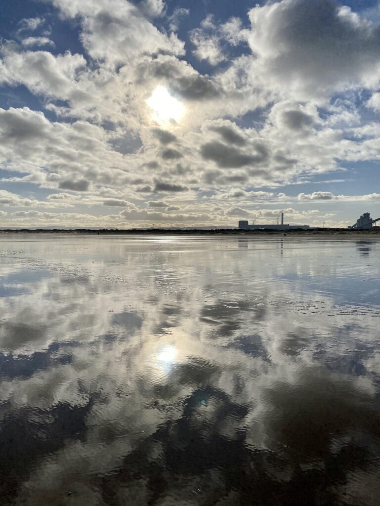 A cloudy sky is reflected in a body of water.