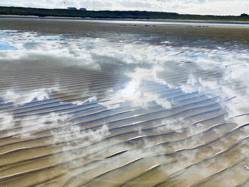 A beach with a lot of sand and a lot of clouds.