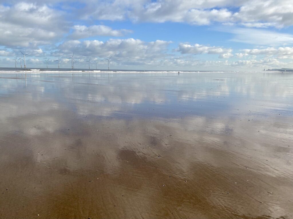 A beach with a lot of sand and a cloudy sky.