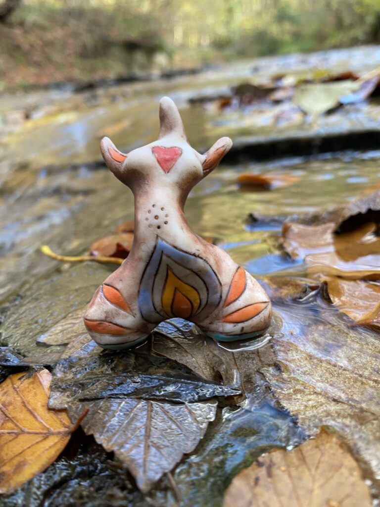 A statue of a deer standing in a stream of leaves.
