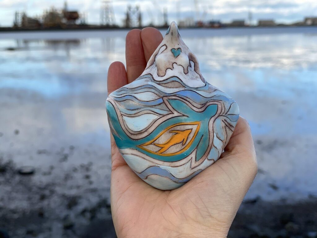 A person holding up a ceramic mermaid figurine.
