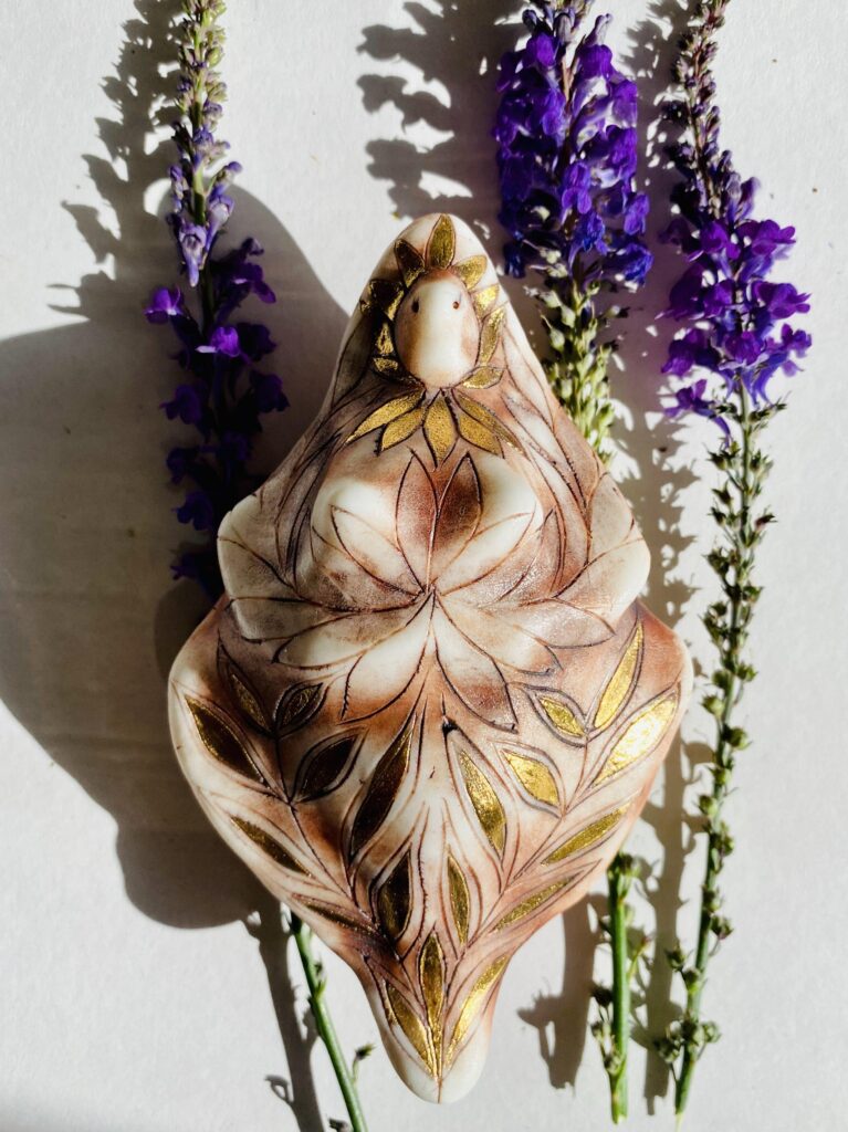 A vase with purple flowers and a figurine on it.