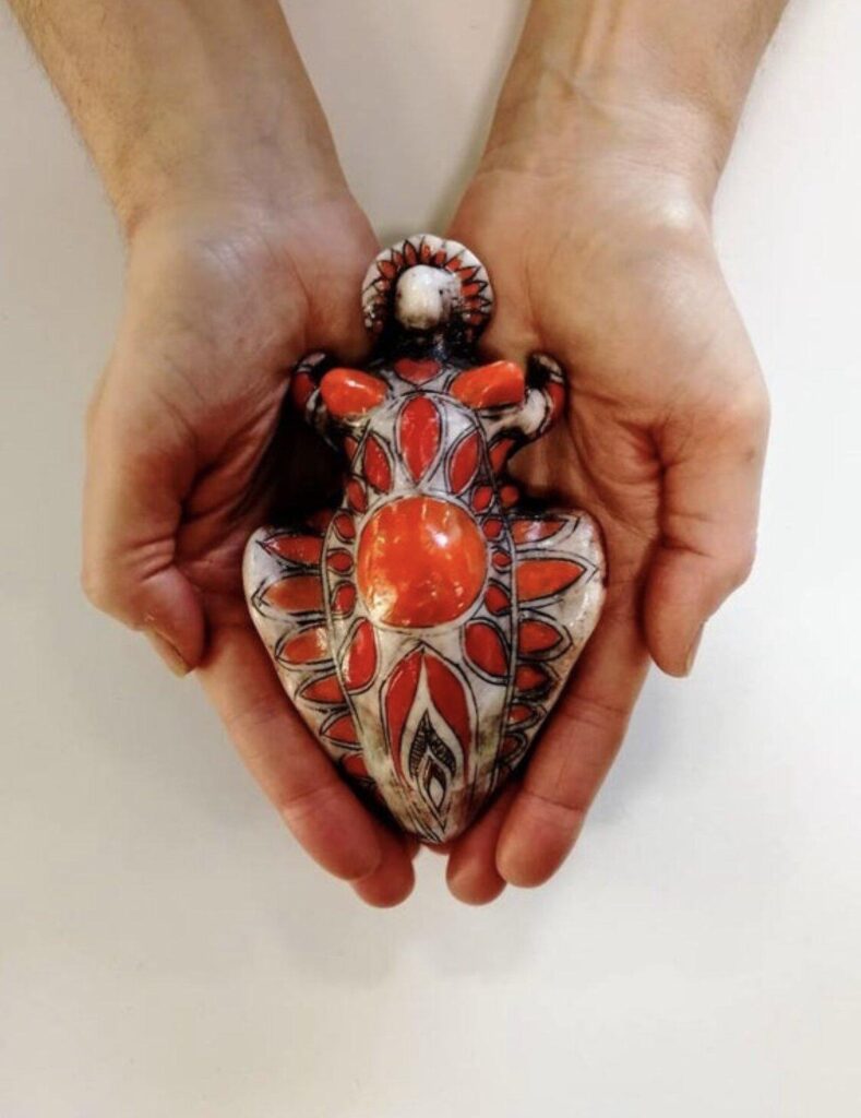 A pair of hands holding a figurine of a frog.