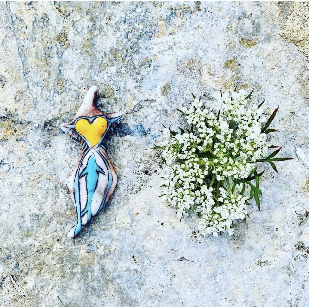 A necklace with a heart on it next to some flowers.