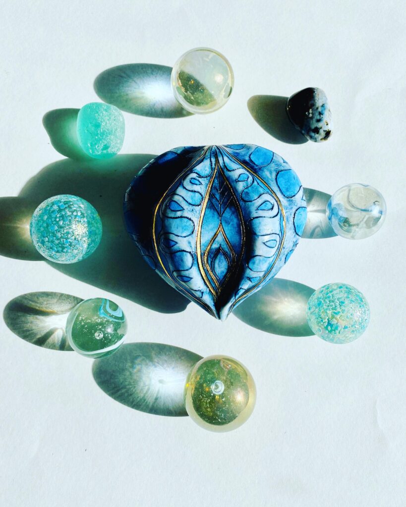A blue glass heart surrounded by other glass objects.