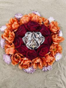 A Yoni Mandala bouquet of orange flowers on the sand.